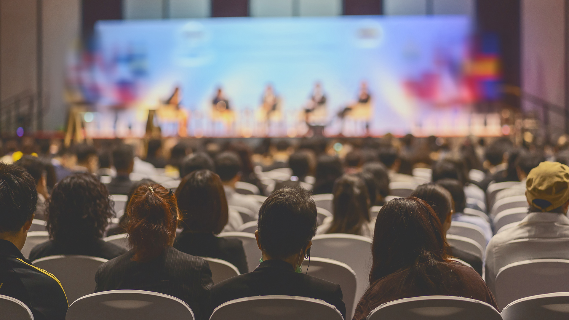 Rear view of Audience listening Speakers on the stage in the conference hall or seminar meeting